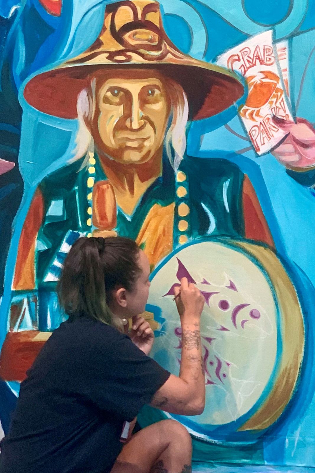 Person painting an Indigenous mural