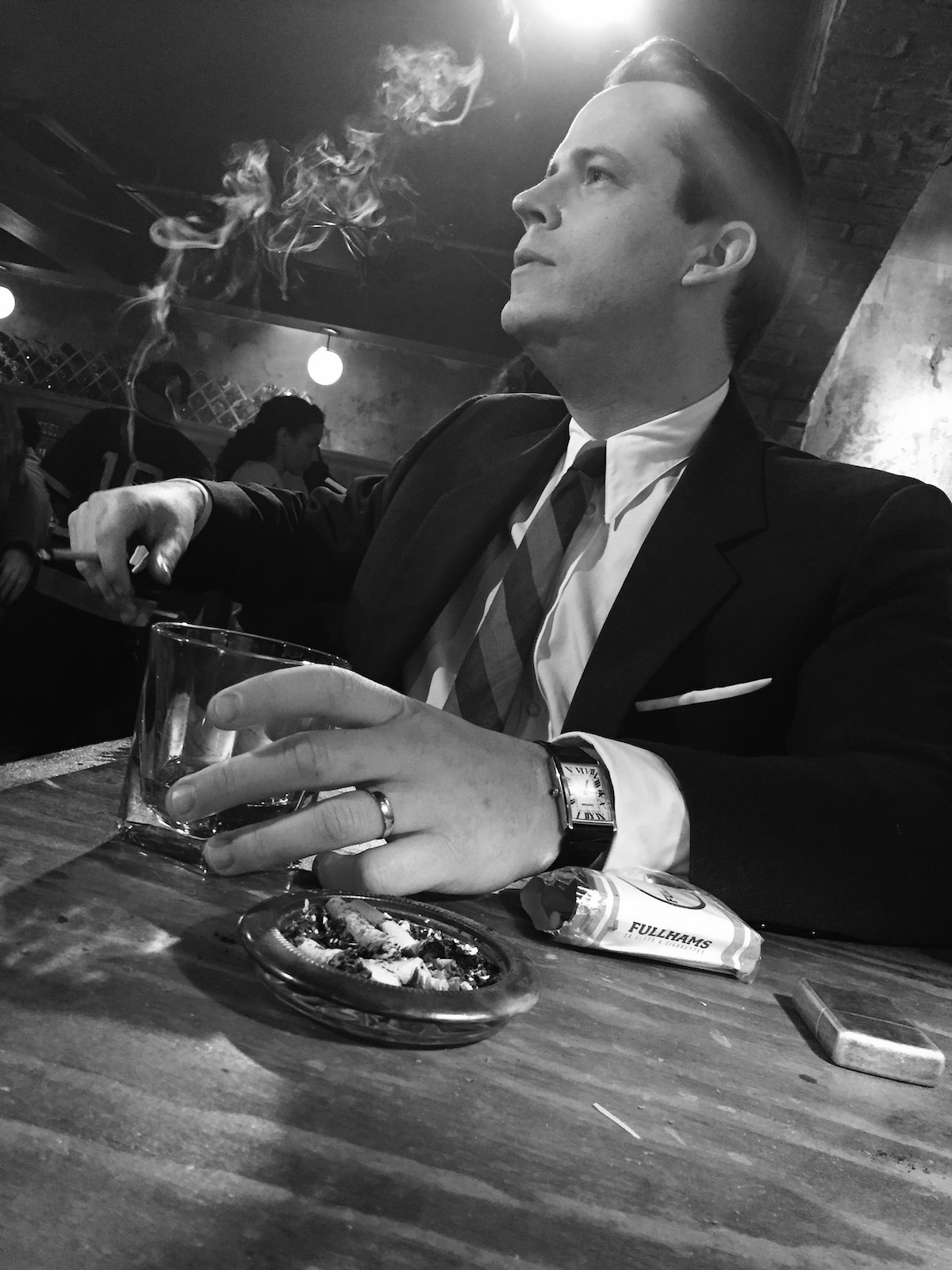 Black-and-white photo of man drinking and smoking