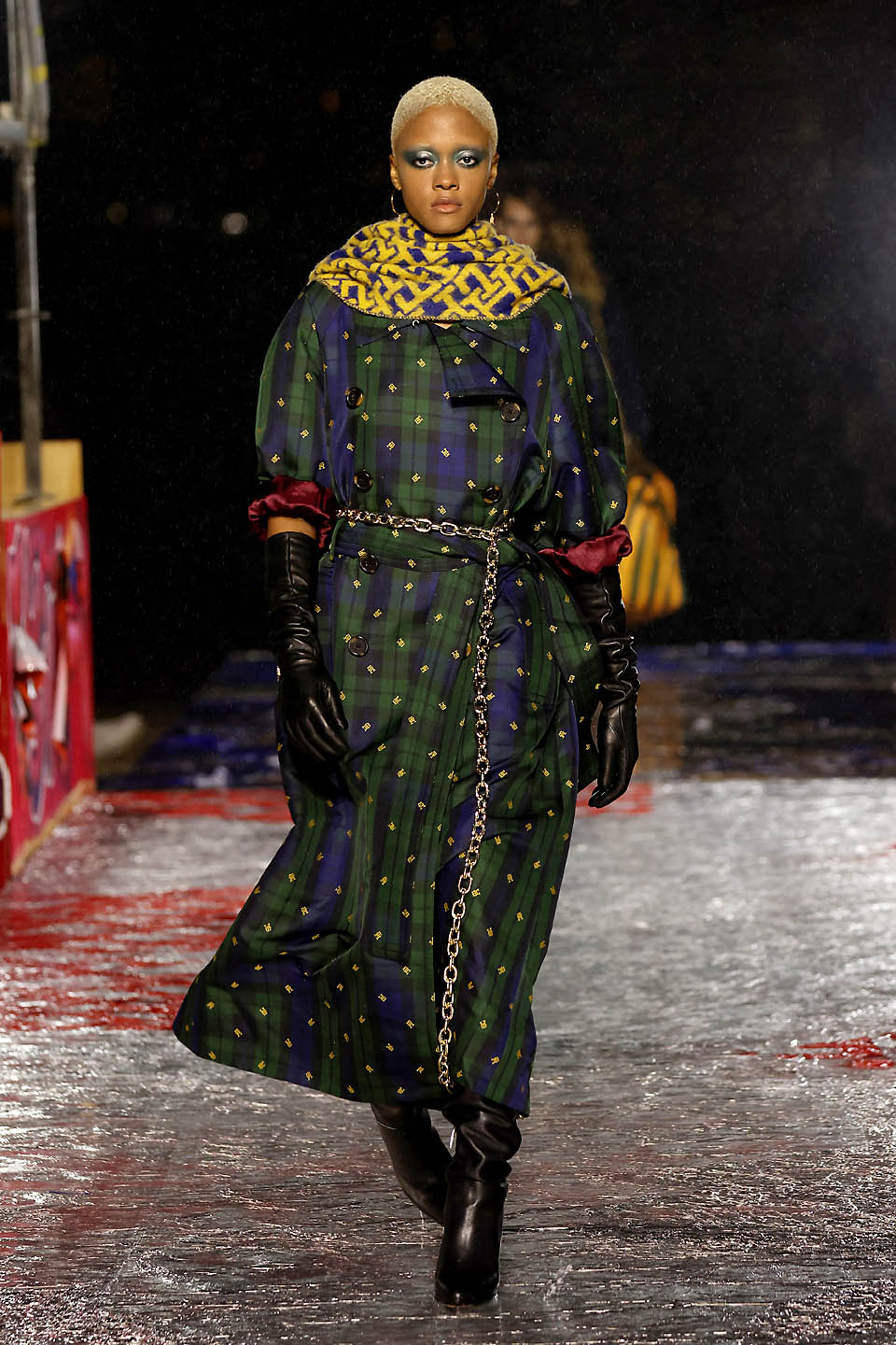 Woman walking the runway wearing a long tartan coat 