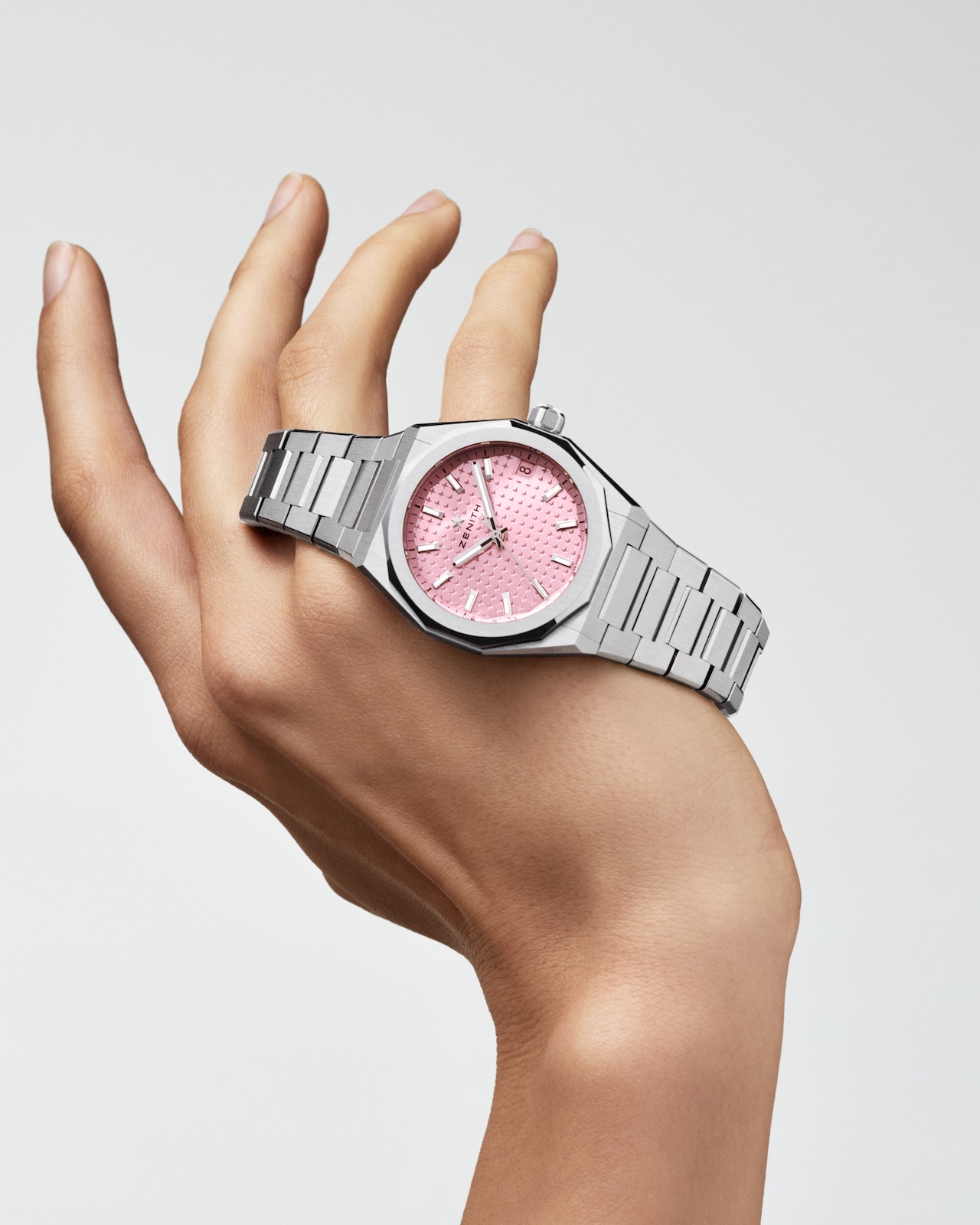 Hand holding watch with pink face