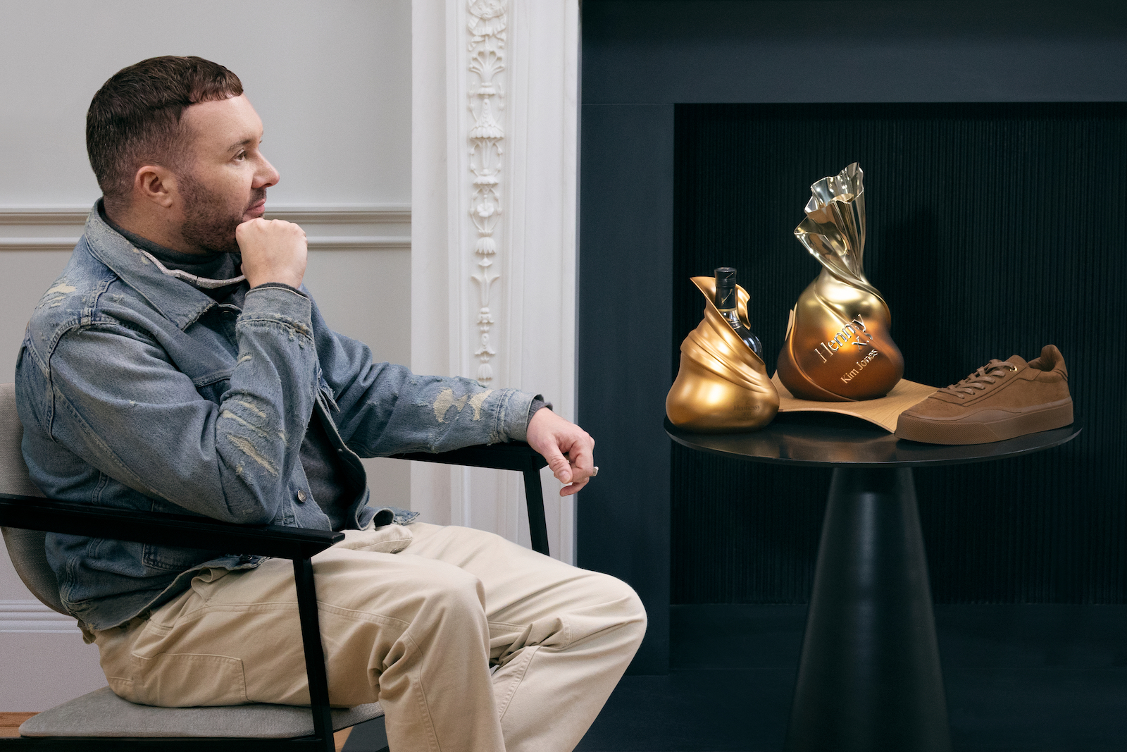 Kim Jones sitting, looking at the three items in the limited-edition collaboration
