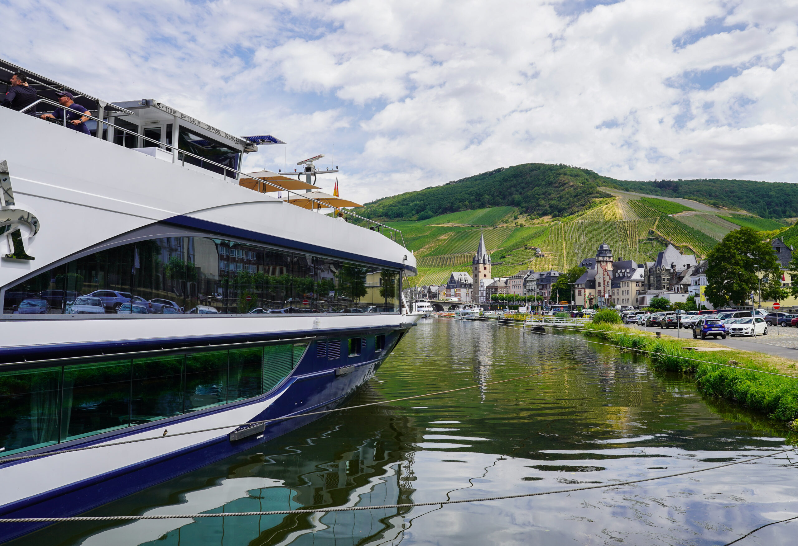 A river cruise ship seen from the side approaching the shore of a town.