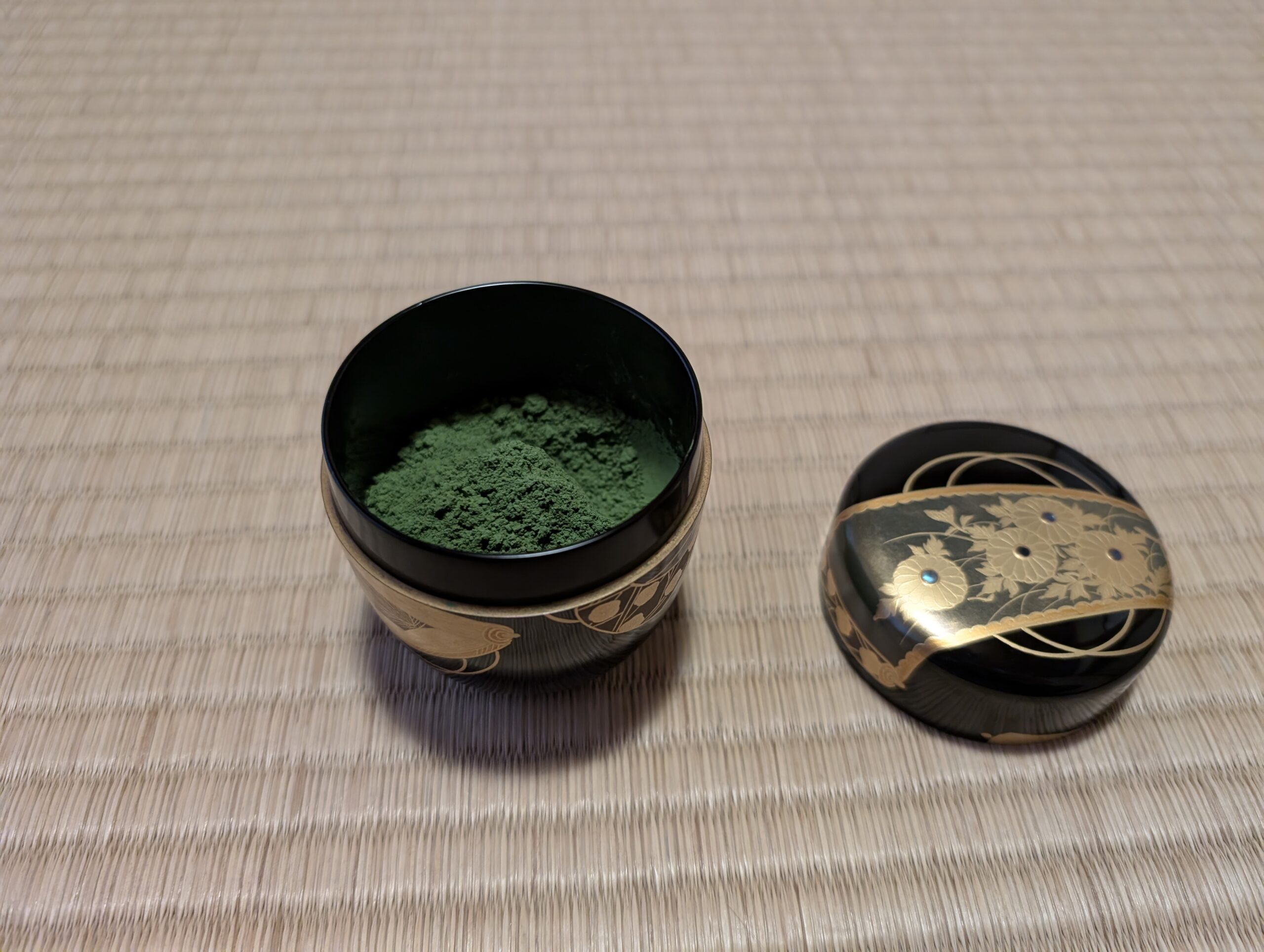 A bowl of ground matcha on a tatami mat.