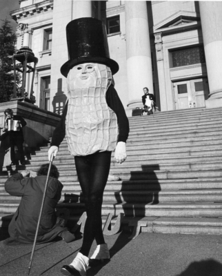 A black and white image of a man in a giant peanut costume, walking down the stairs of the Vancouver Courthouse.