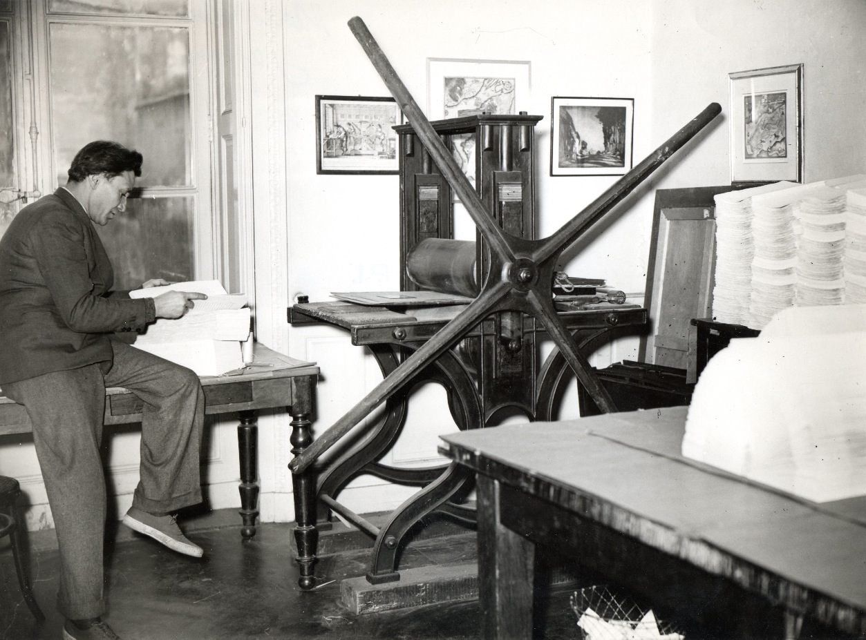 A man, Enrico Tallone's father, sits at typesetting machinery in a black and white photo.