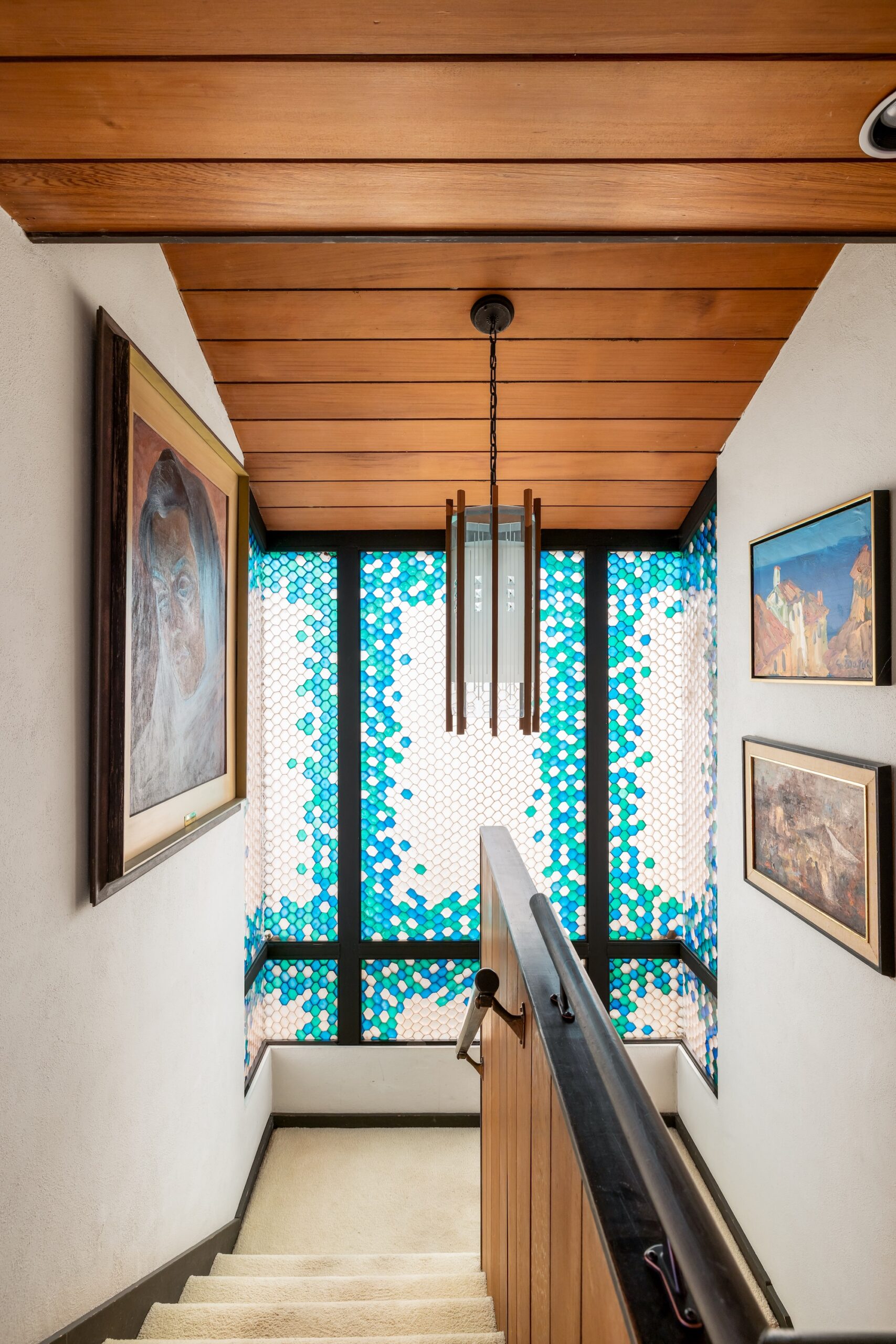 The interior of the Dodek house, designed by Ron Thom. A stained glass window and modern chandelier in a stairway.