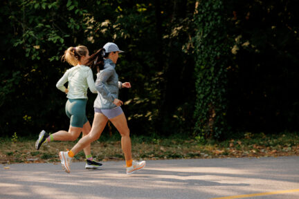Two women in activewear and Hettas sneakers run together outdoors.