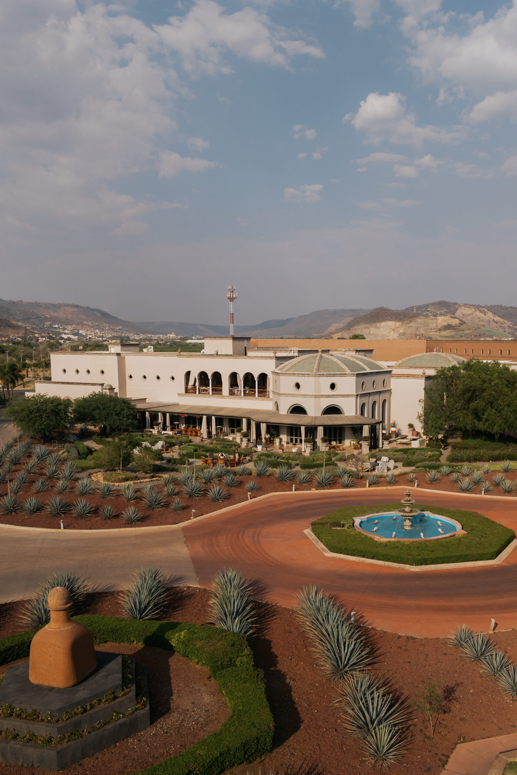 An aerial shot of Hacienda Patrón, a large estate in Mexico, surrounded by agave plants and a fountain.