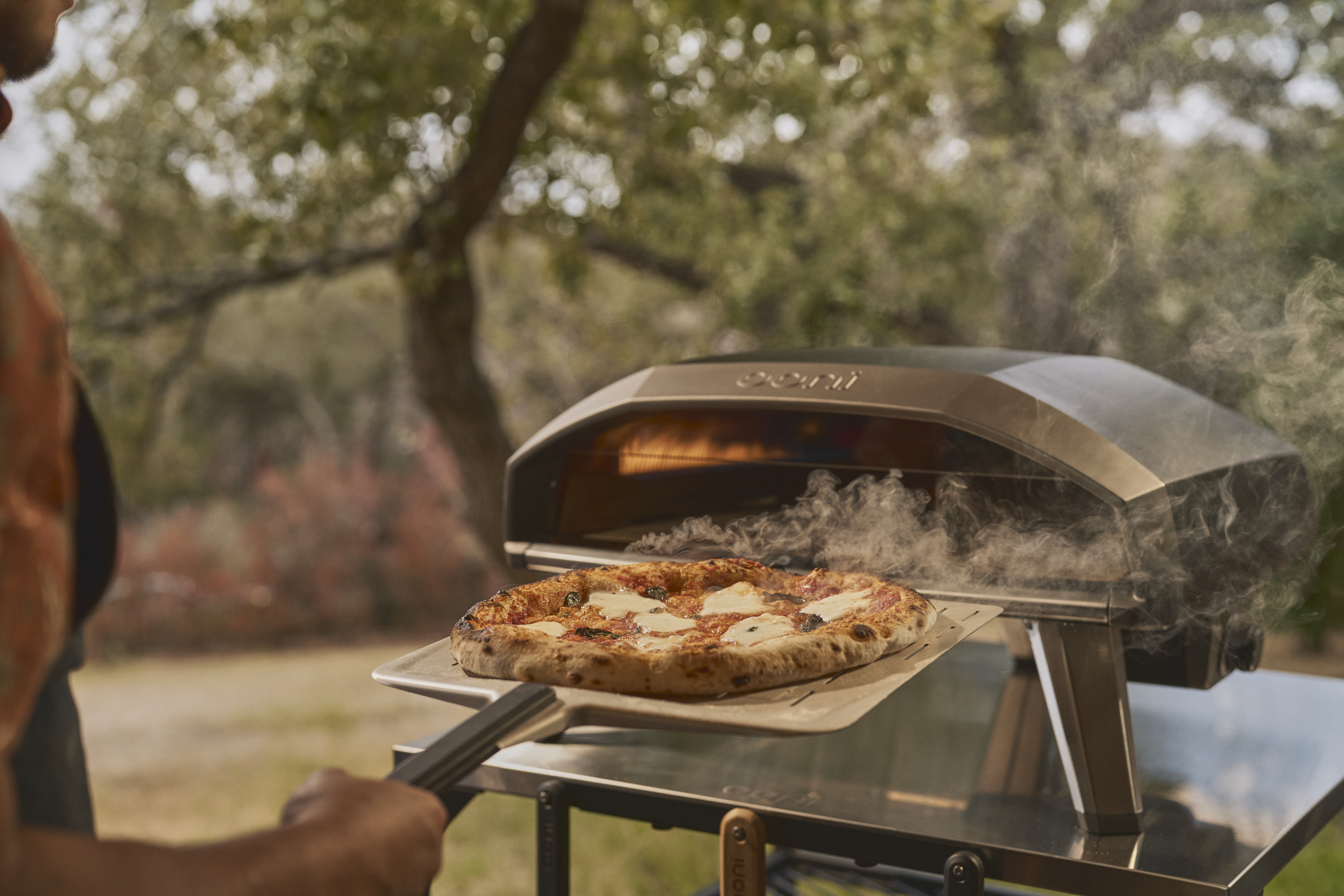 A pizza comes out of an Ooni pizza oven