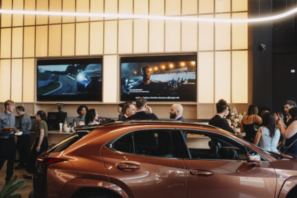 A brown care on display in front of a crowd of guests at the Lexus Studio.