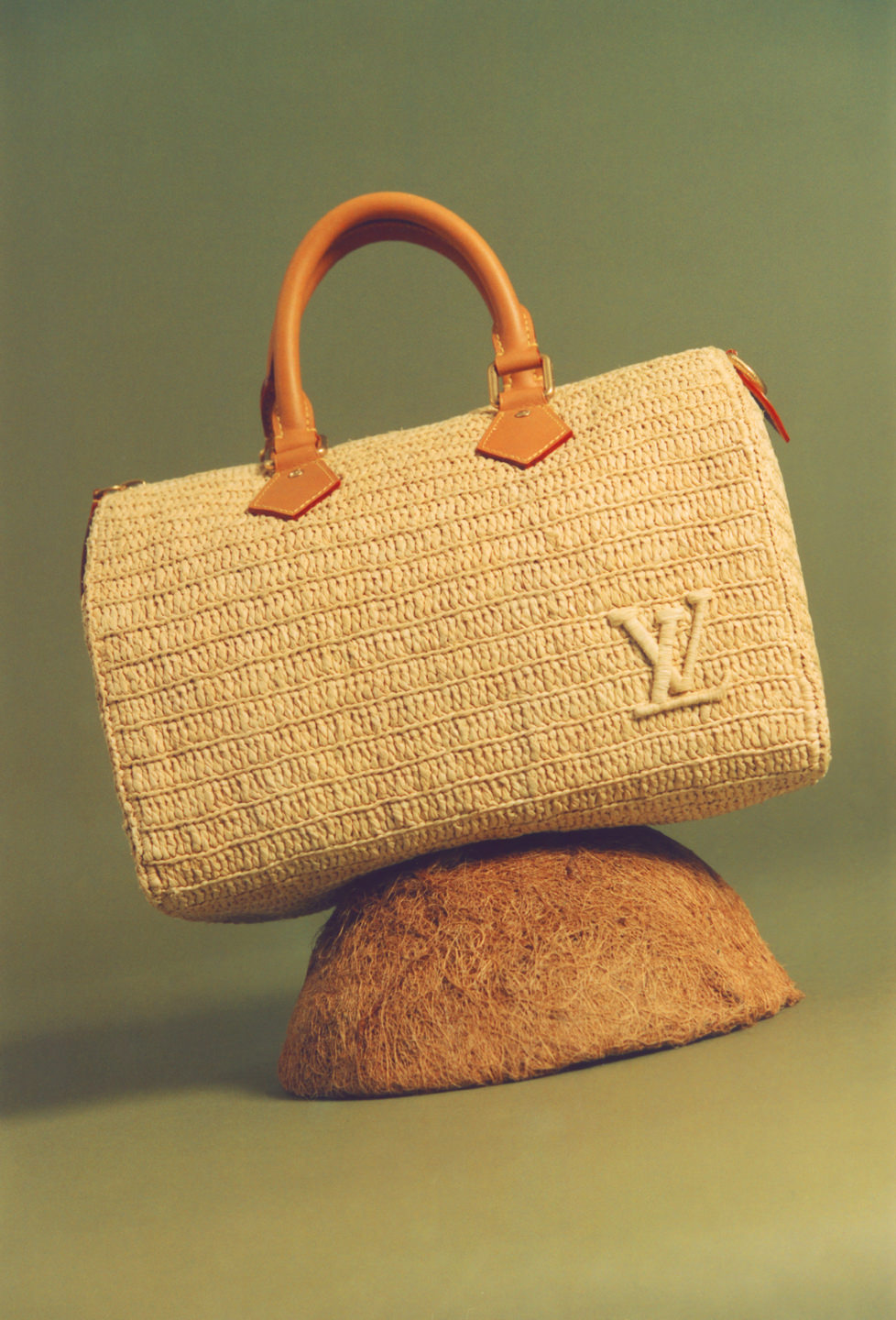 A tan Louis Vuitton bag with a leather handle perched atop a felted dome.