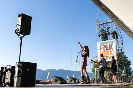 A singer stands onstage with her fist in the air at the Vancouver Folk Festival