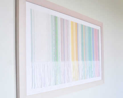 A framed piece of textile art hanging on a white wall.