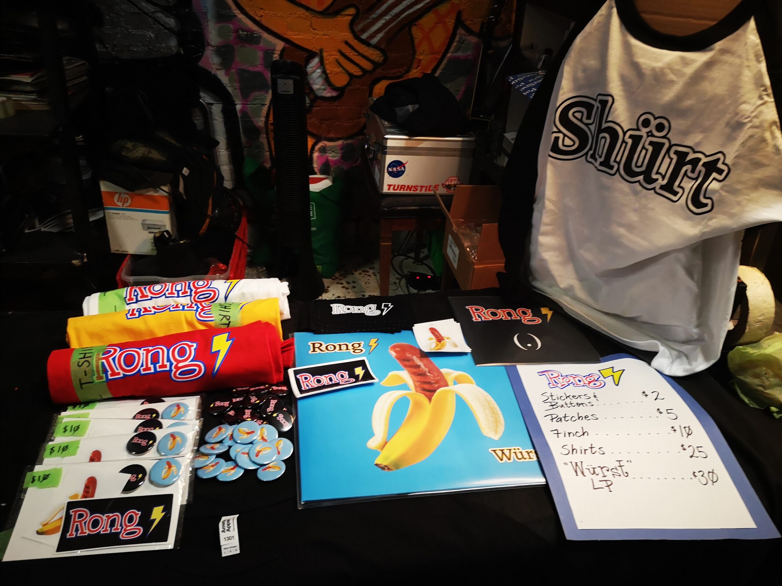 A merch table features albums and shirts promoting the band Rong.