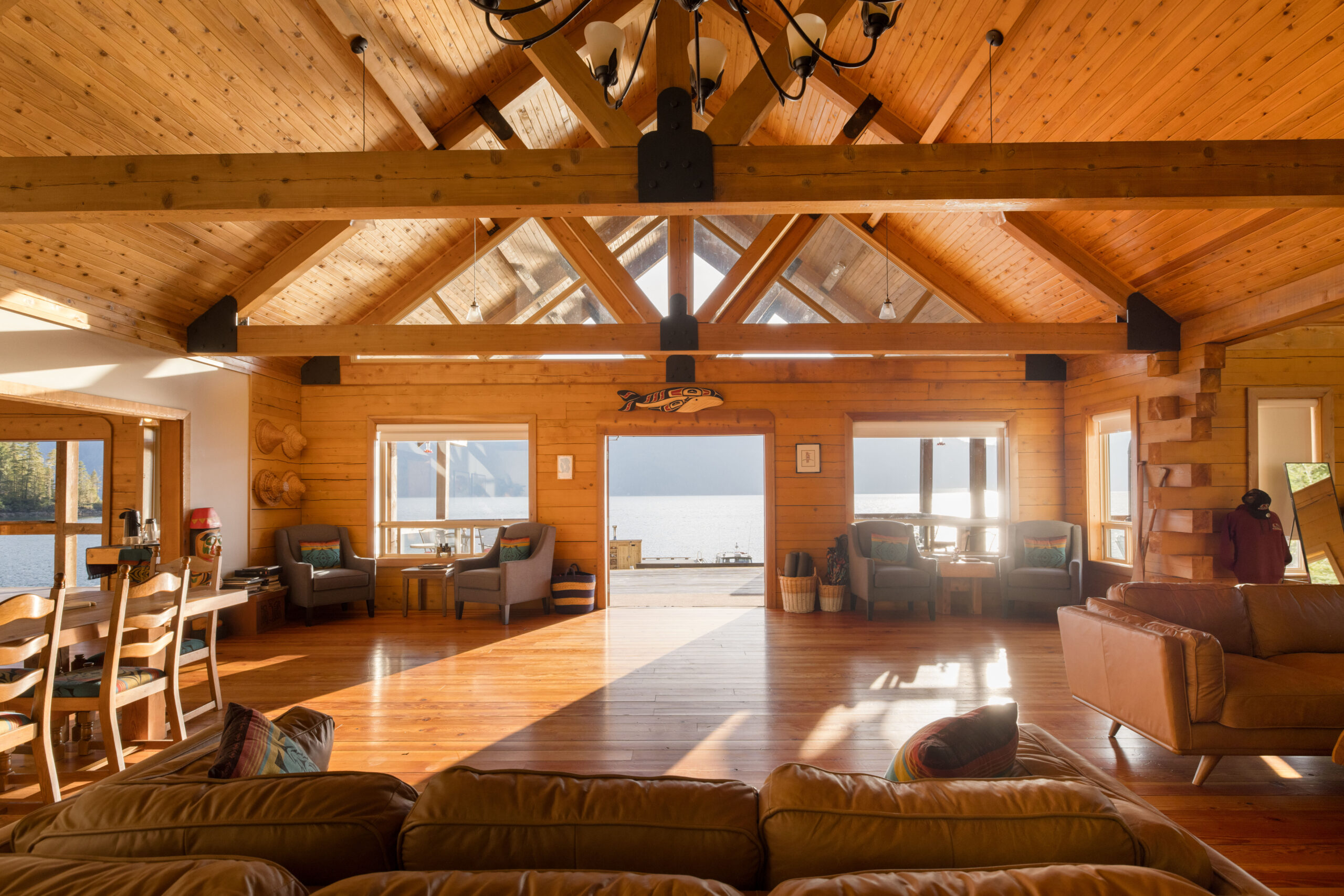 Interior of a cedar lodge looking out onto water and mountains.