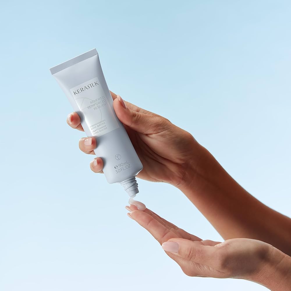 A woman's hands hold a bottle of shampoo.