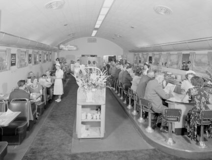 The interior of Clancy's Sky Diner. Patrons eat at tables and a bar.