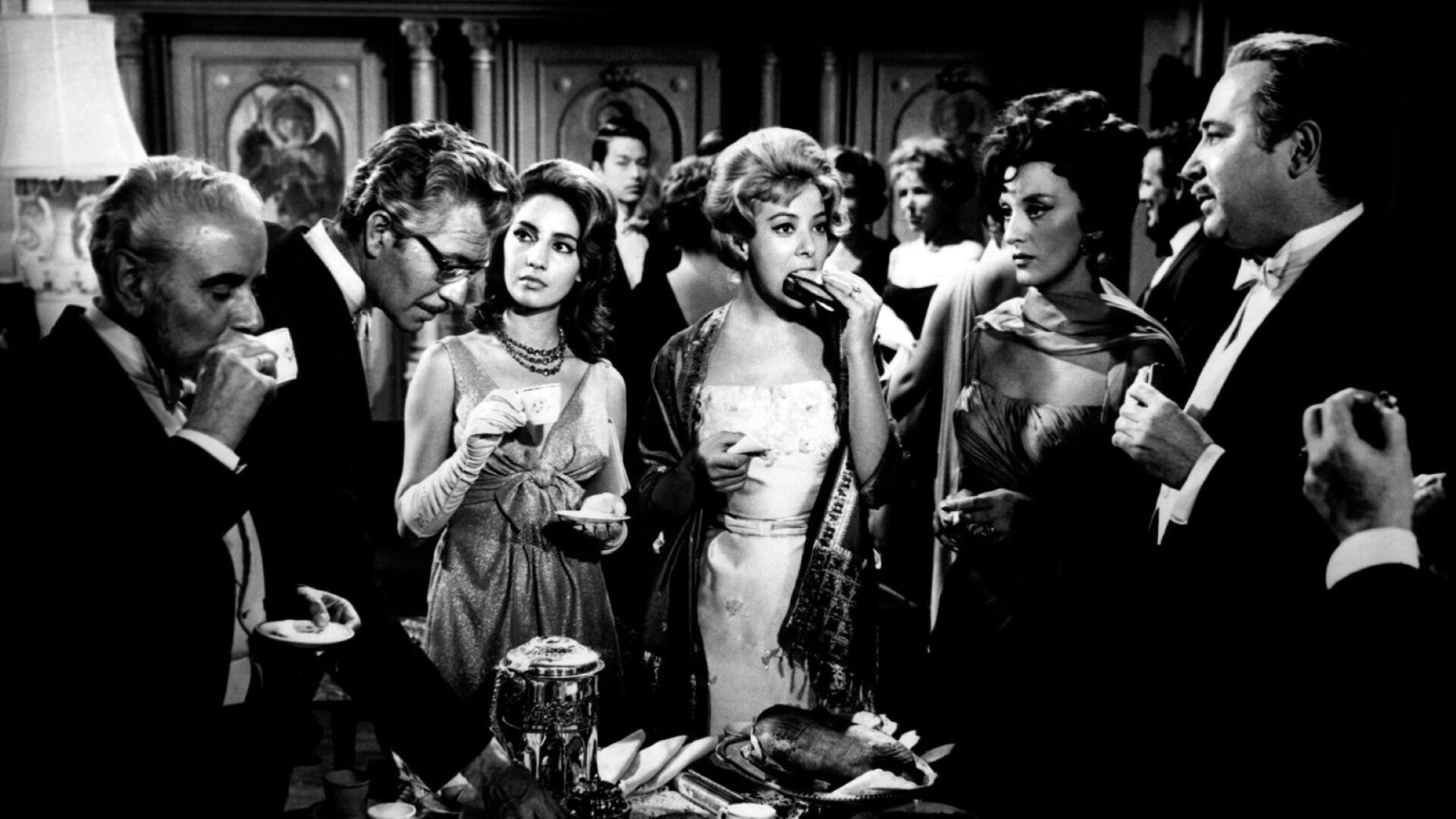 A black and white still of people at a dinner party in the film The Exterminating Angel.