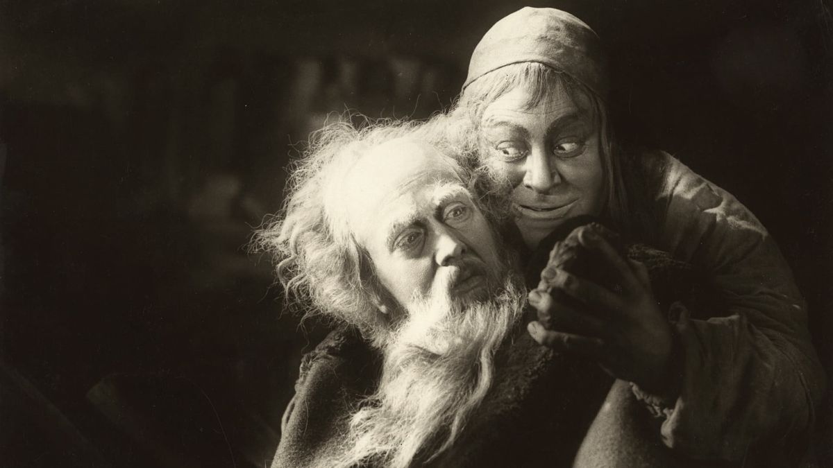 A scene from the film Faust, with two men close together.