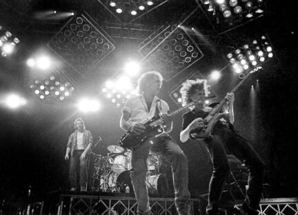 A black and white photo of the band Loverboy performing on stage.