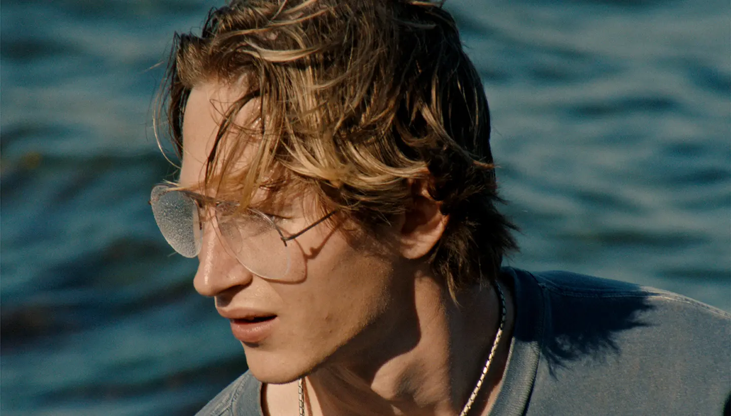 A close-up of a man wearing glasses in a still from Blue Heron.