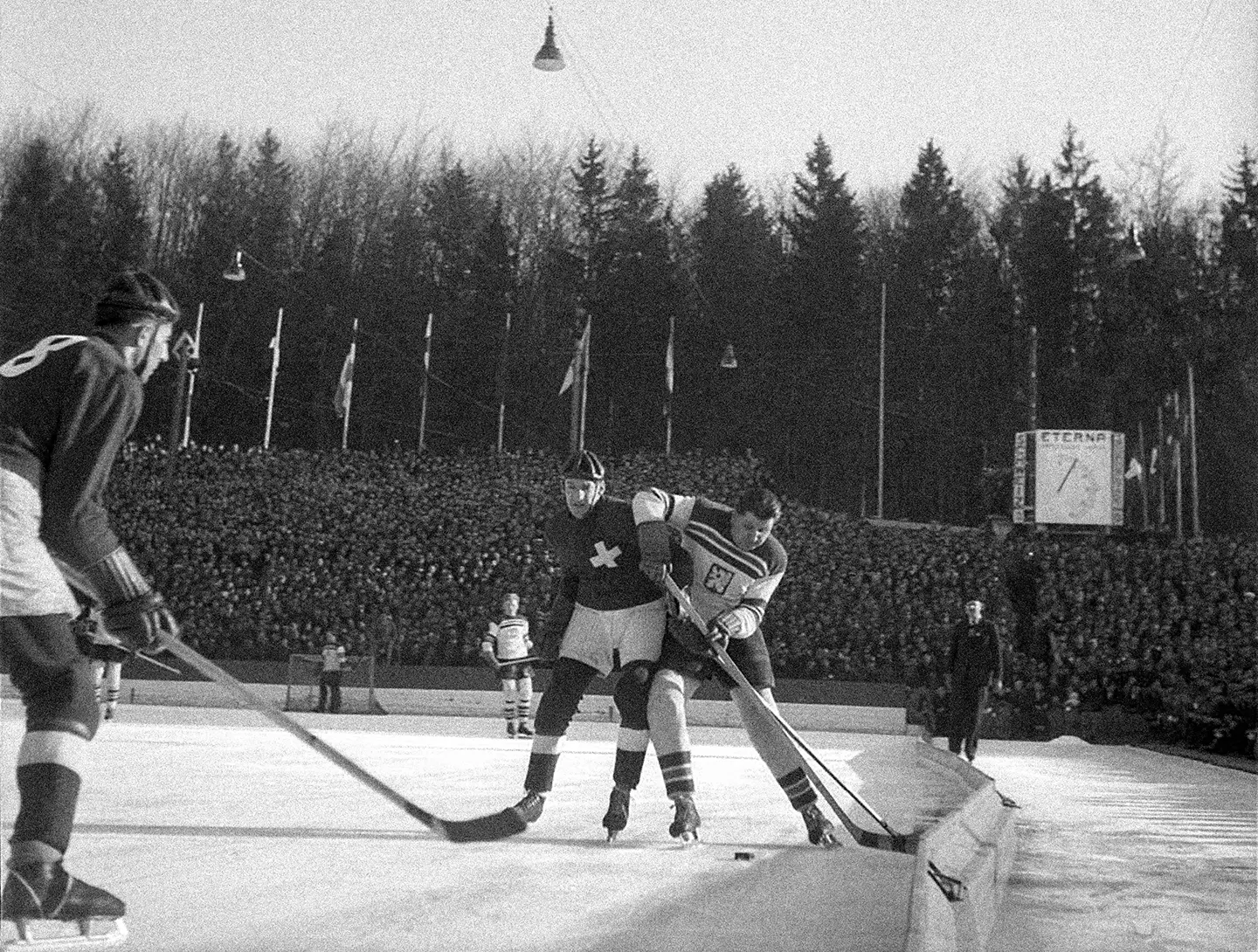A black and white photo of men playing hockey outdoors.