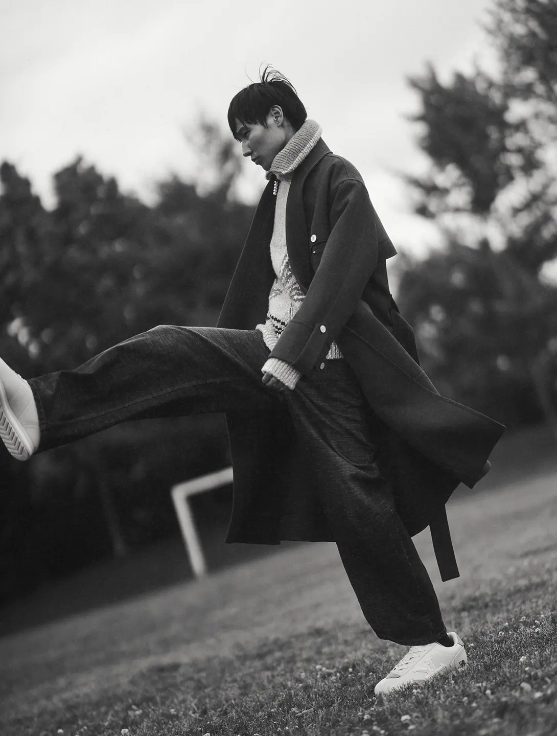 A black and white photo of a man kicking one leg up.