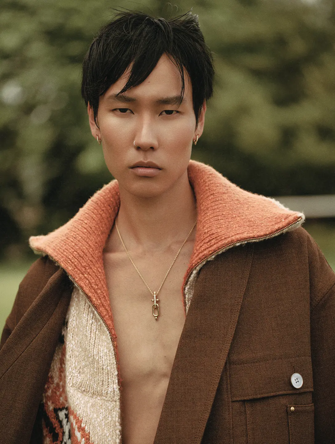 A man in a brown jacket looks into the camera.