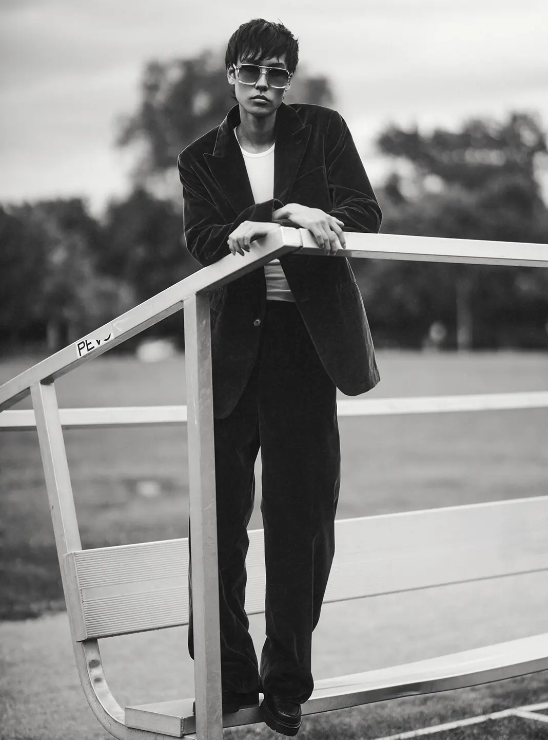 A black and white fashion shoot photo of a man in a suit and sunglasses looking into the camera.