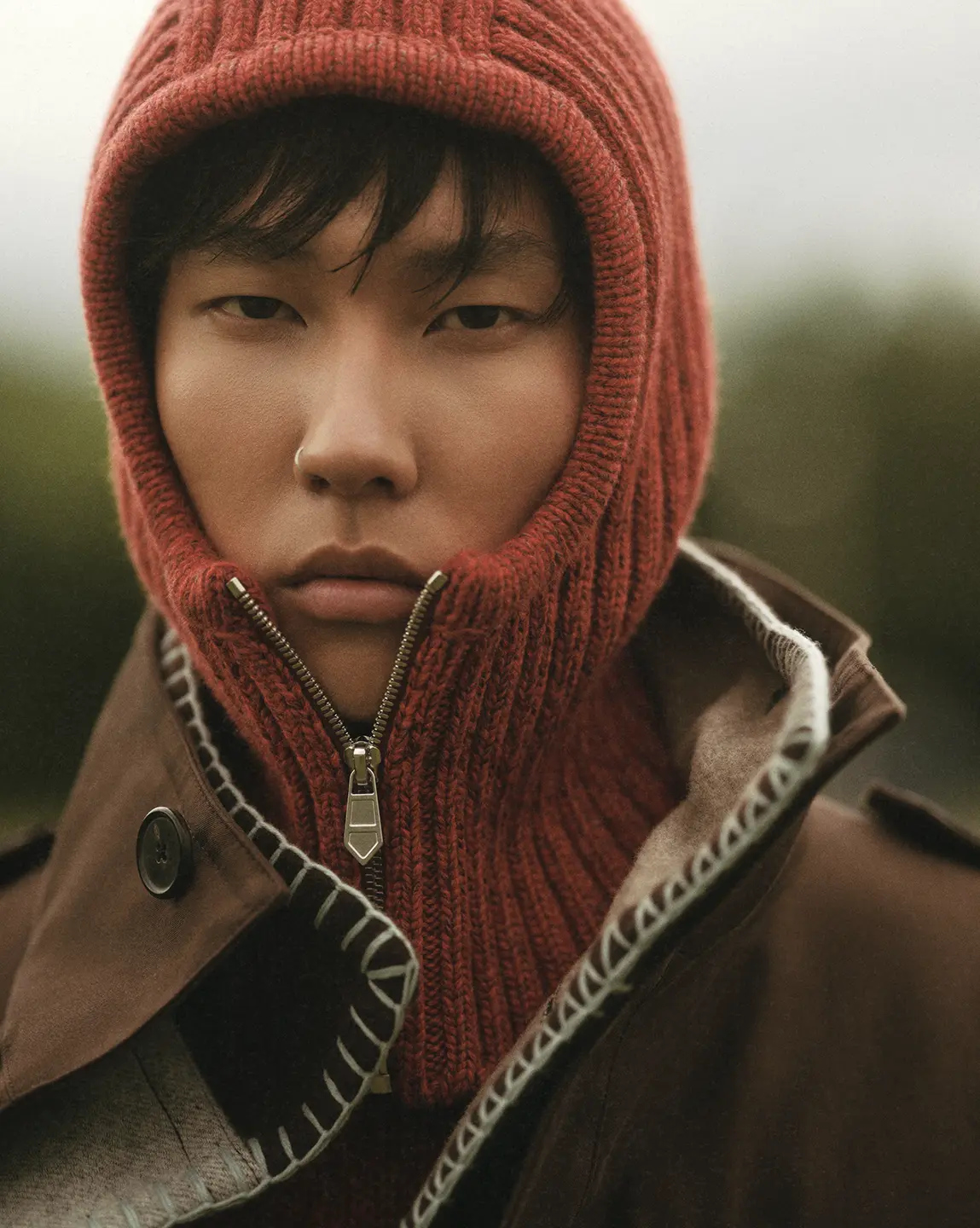 A man in a knit, zippered hood looks into the camera.