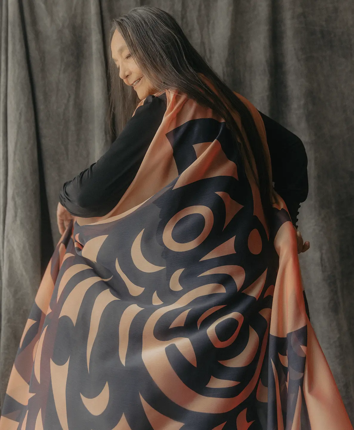 A woman turns, holding her long, flowing dress.