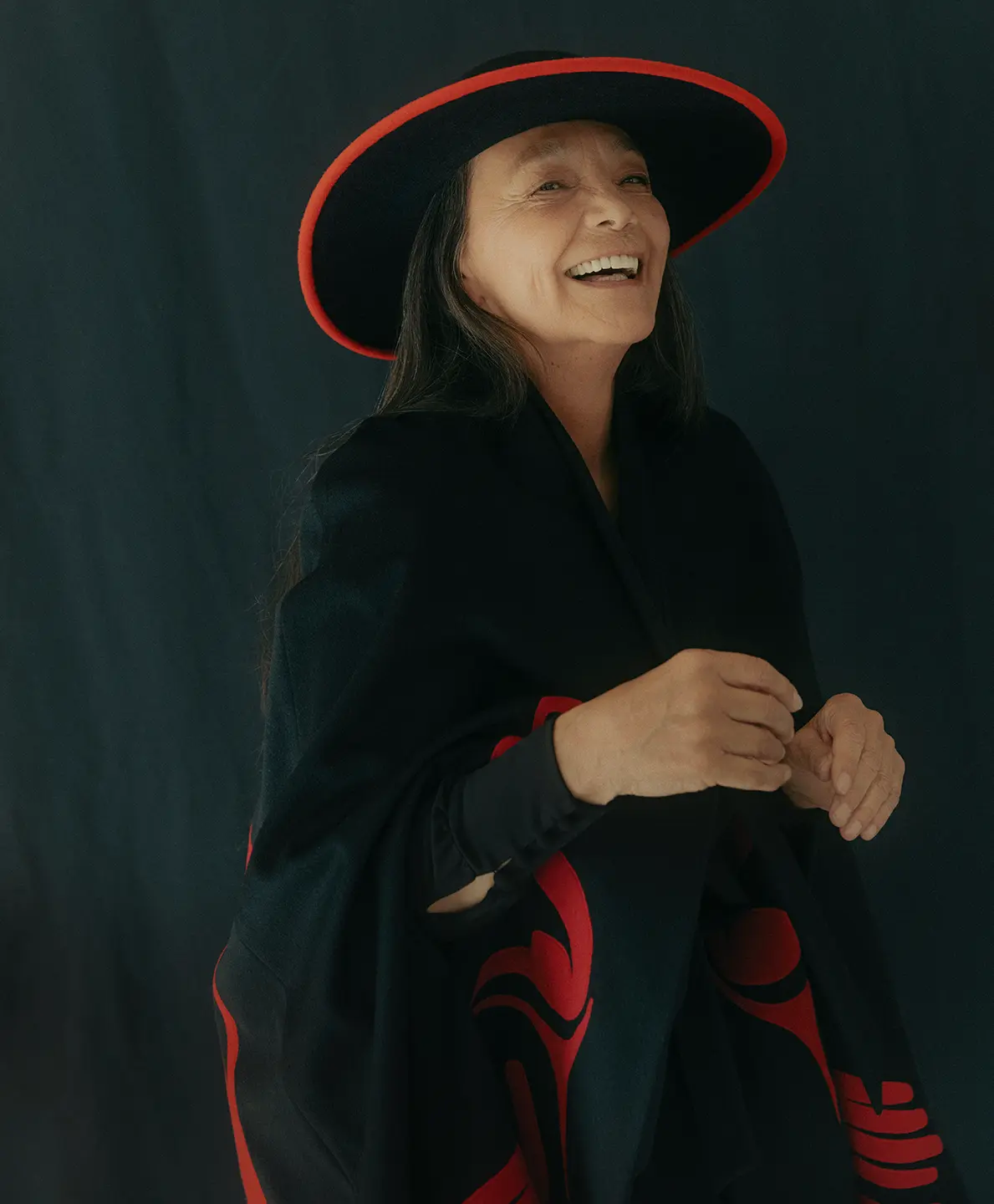 A woman in a black and red outfit laughs.