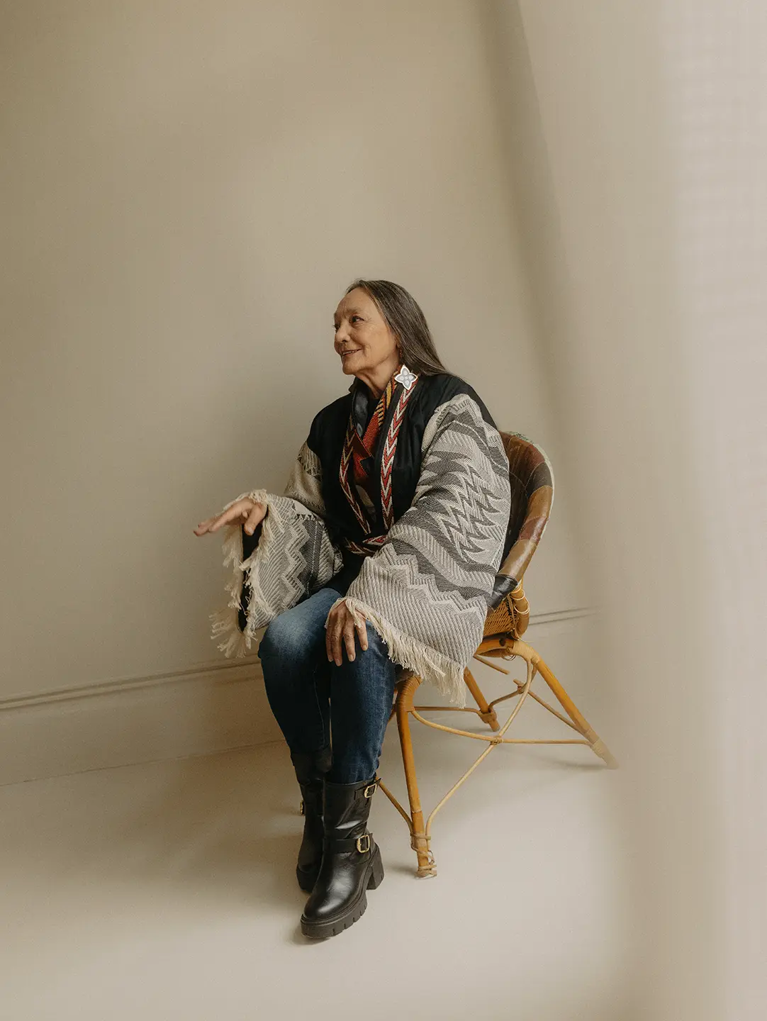 Tantoo Cardinal is seated in a chair, speaking to someone out of frame.