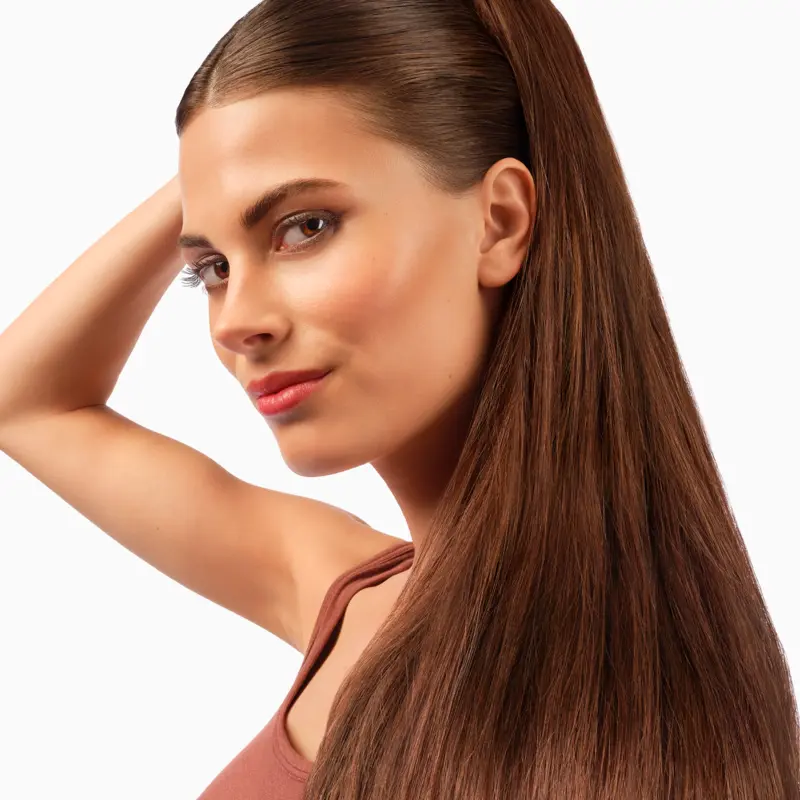 A woman runs her hand through her long brown hair.