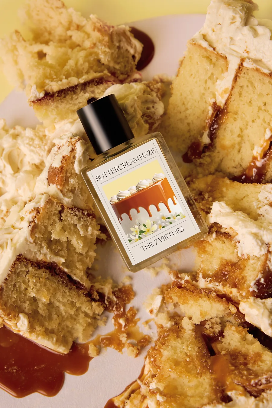 A bottle of perfume labelled Buttercream Haze, The 7 Virtues. The bottle is atop a caramel, buttercream cake.
