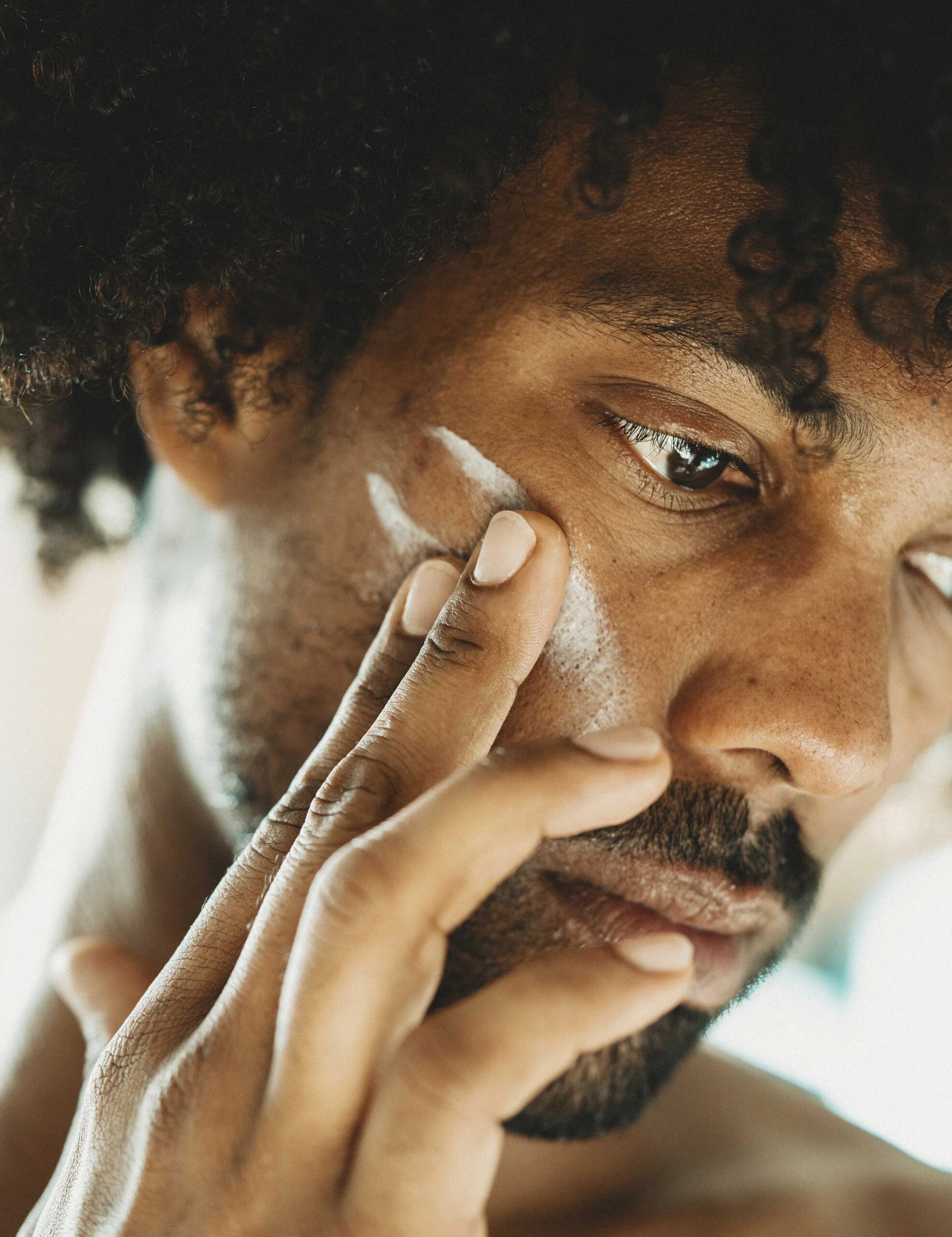 Close up of a man applying beauty products to his face.