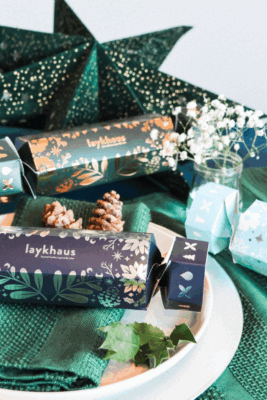 Boxes shaped like Christmas crackers arranged on a Christmas table setting - holiday gift guide.