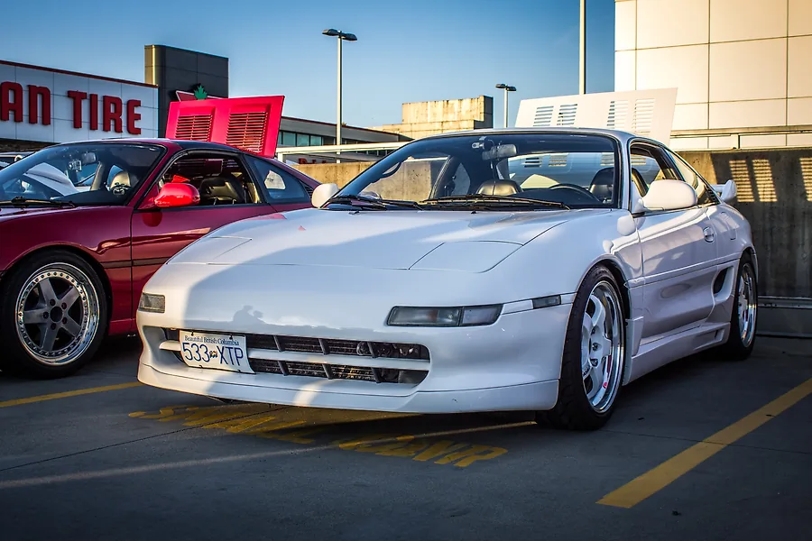 A red car and a white car parked side-by-side in a Canadian Tire parking lot.