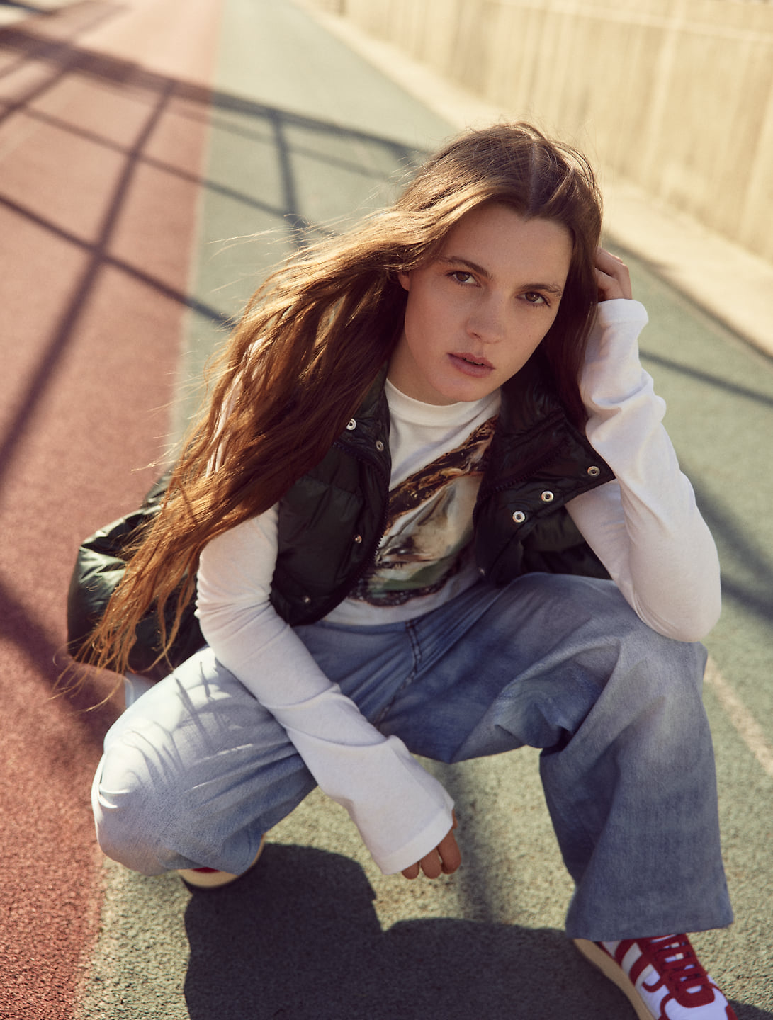 A woman crouches, looking at the camera.