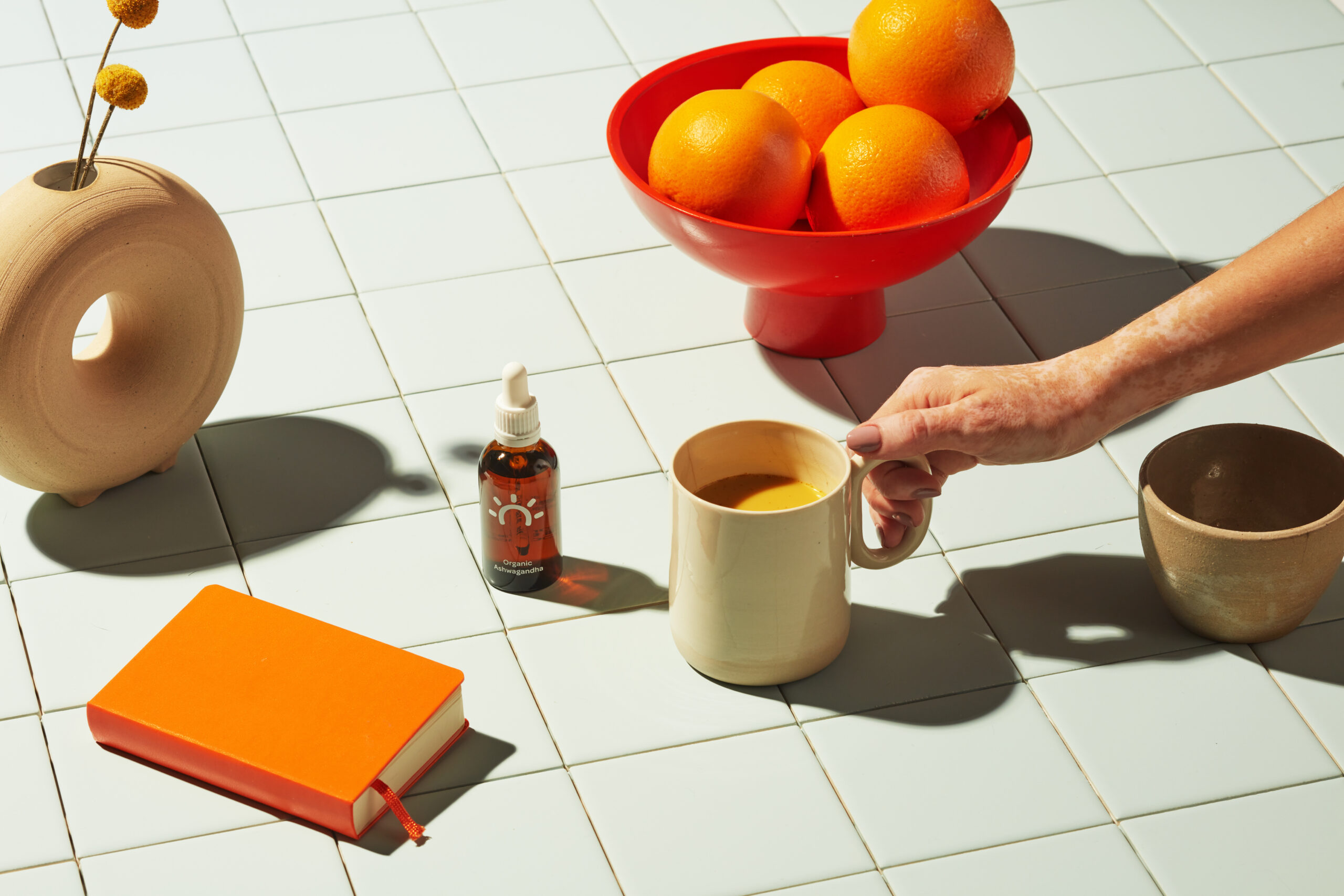 A checkered tabletop is covered in fruit, drinks, and tinctures - holiday gift guide.