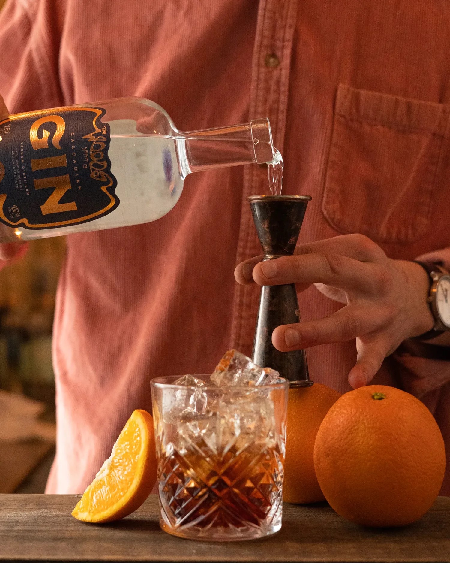 Hands pour gin into a cocktail.