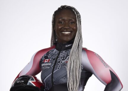 Cynthia Appiah oises in her olympic uniform, holding her helmet at her side.