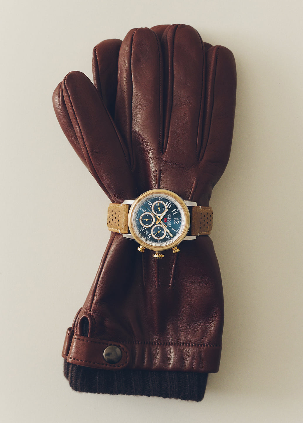 A wristwatch on a brown leather glove.