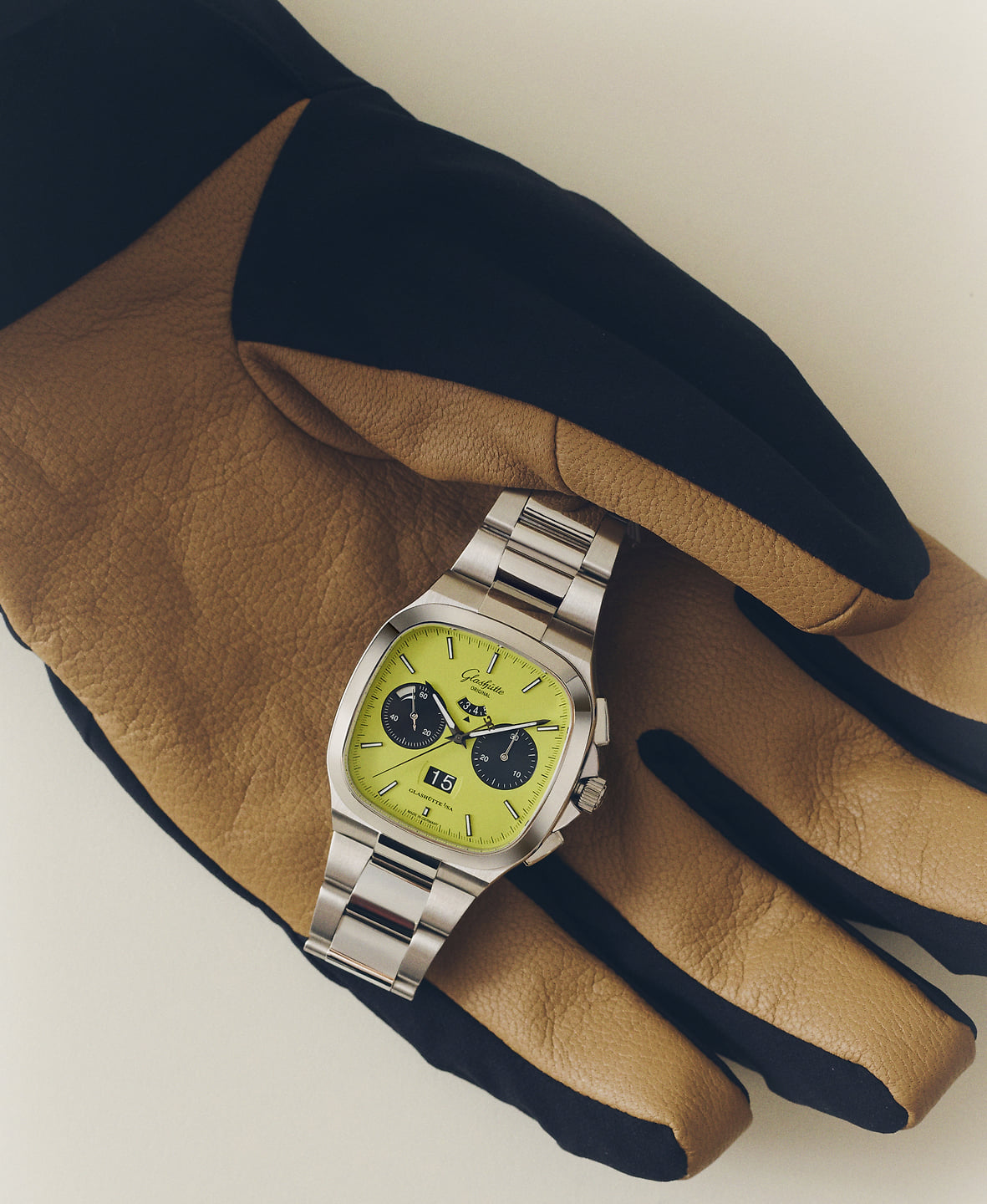 A silver watch on a brown leather glove.