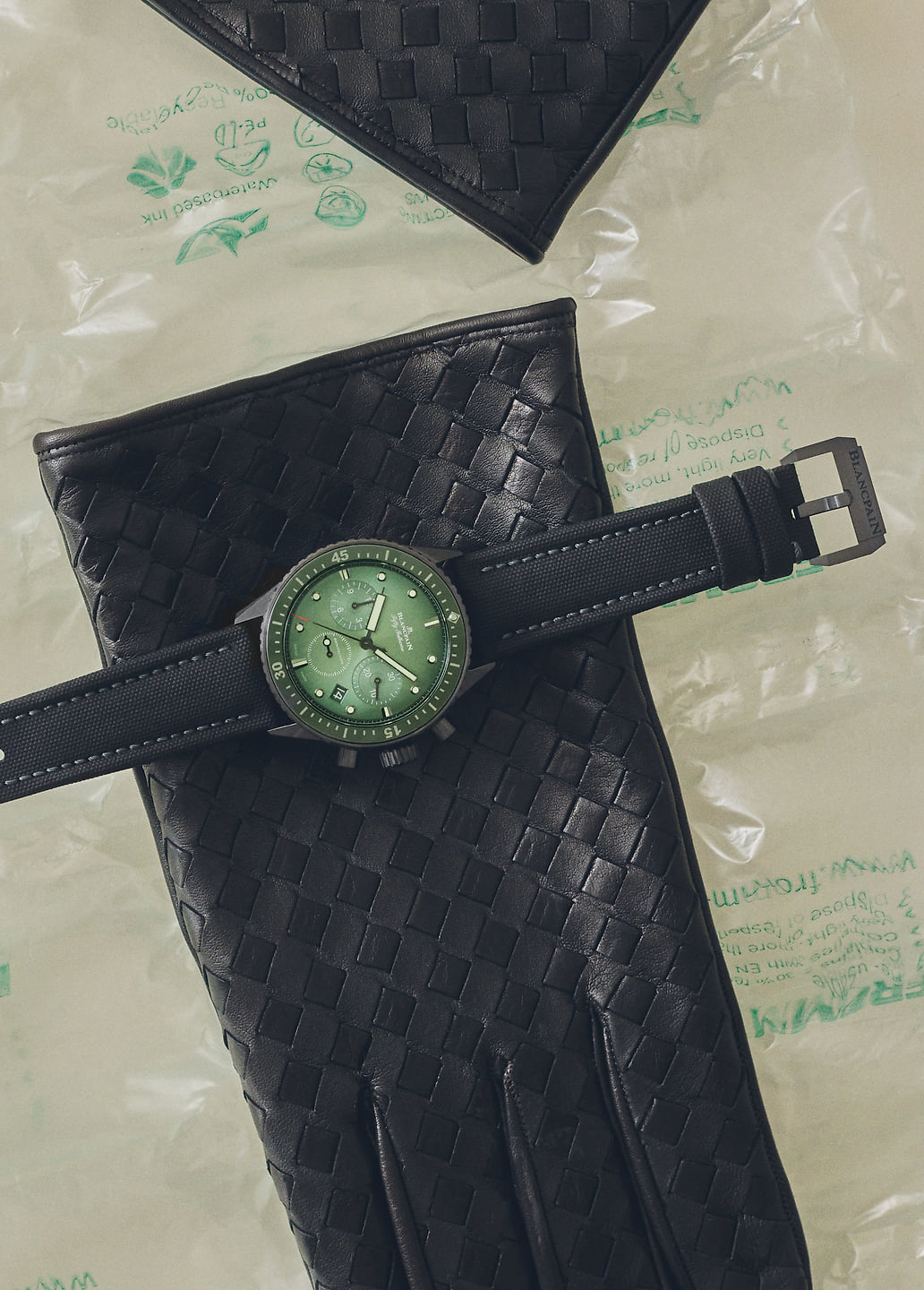 A chronograph watch on a black leather glove.