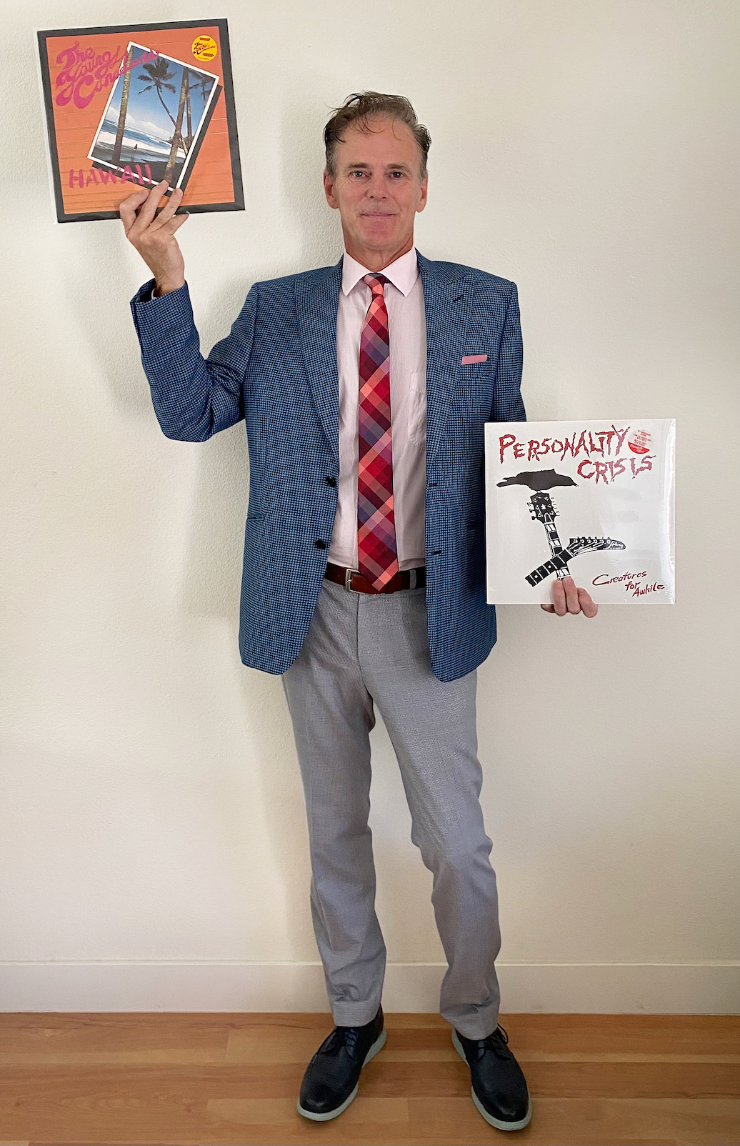 A man in a sport jacket holds up two records from Porterhouse Records.