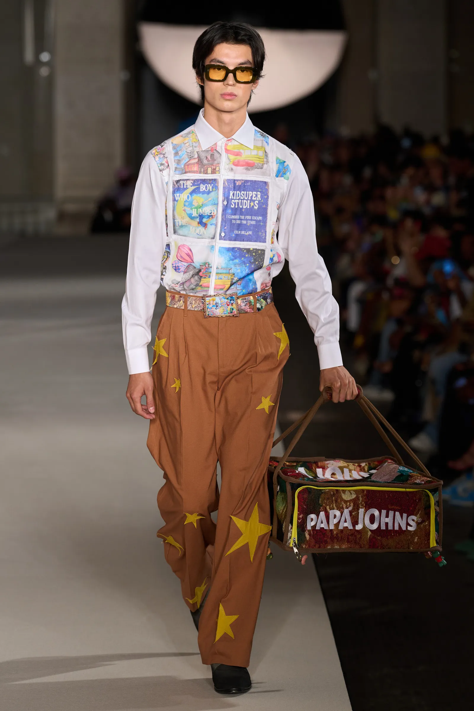 A model walks the runway in a literature-emblazoned shirt.