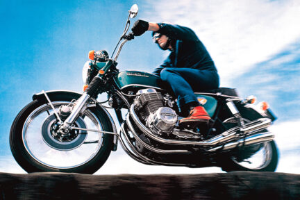 A man sits atop a Honda CB750 superbike motorcycle.
