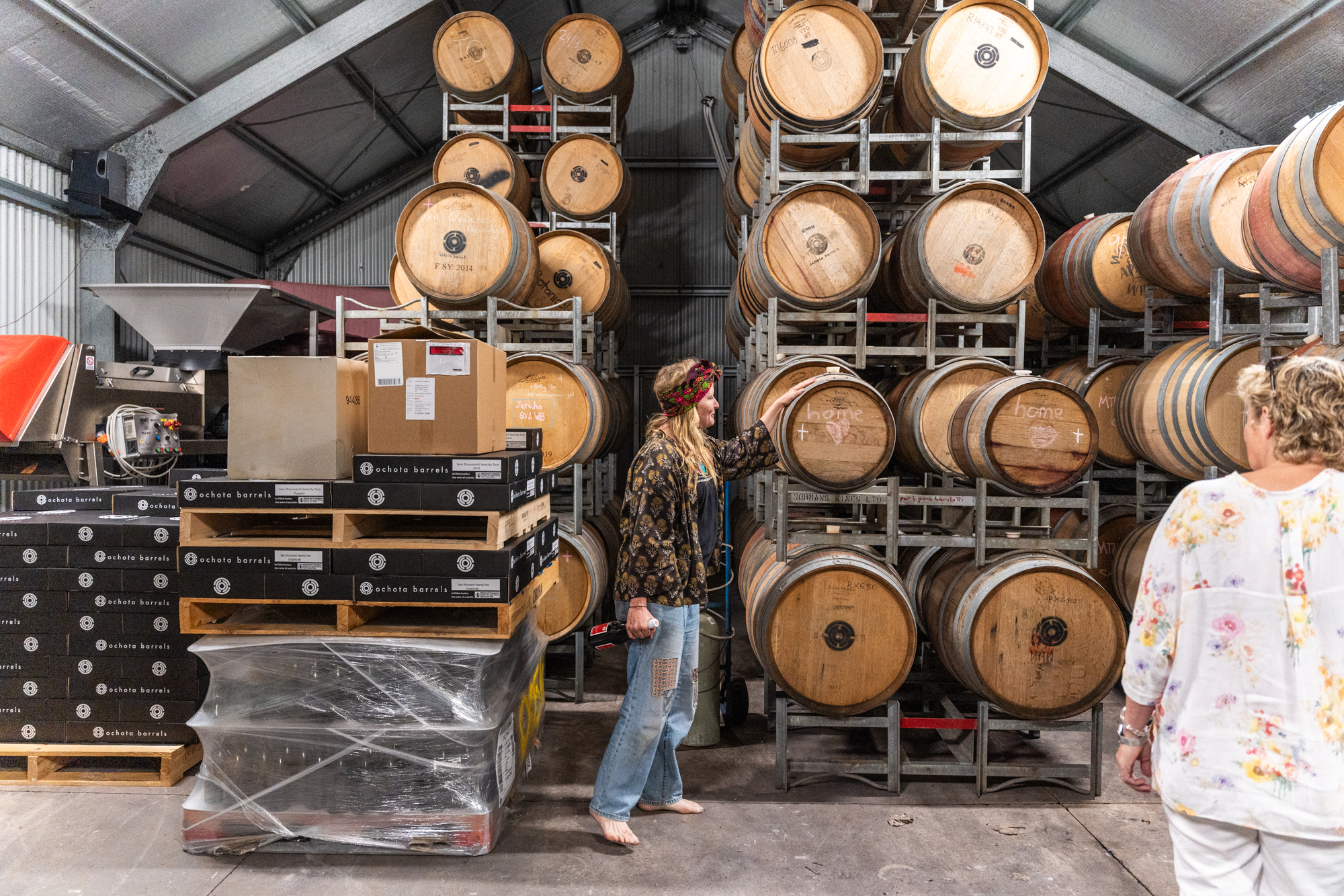 A woman stands in front of wine barrels.