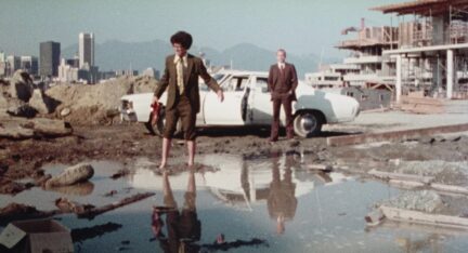 A man and woman stand outside a car in the movie Skip Tracer.